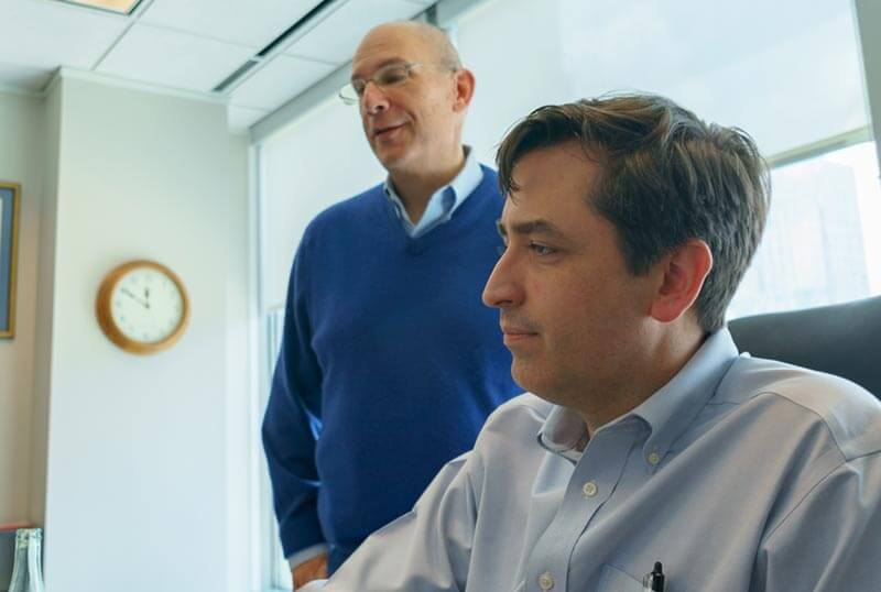 paul skeith and jim howicz discussing and working in front of a computer screen