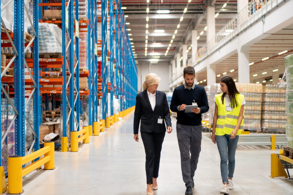 three people walking through a manufacturing facility