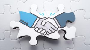 two shaking hands on puzzle pieces, signifying the final step of a partnership