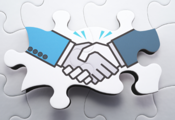 two shaking hands on puzzle pieces, signifying the final step of a partnership